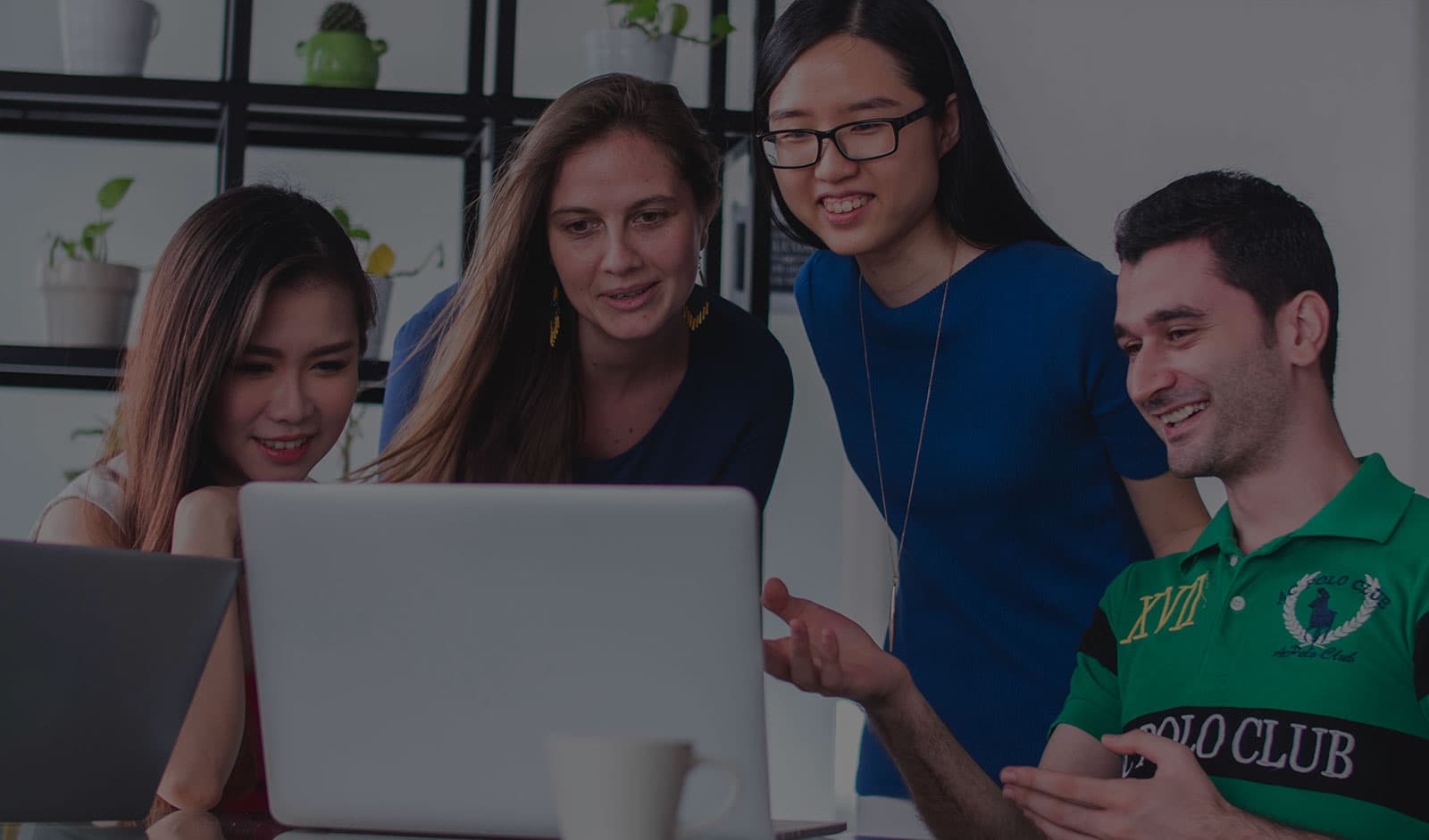 A group of students discussing something on a laptop