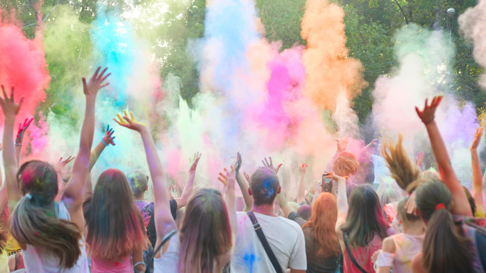 People wave their arms in the air as colorful dust flies