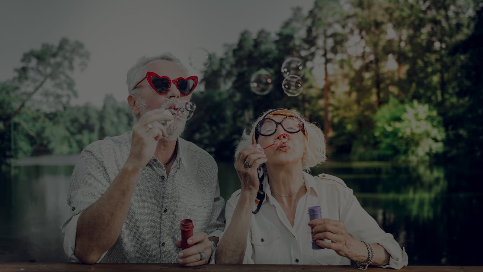 A couple wearing wild sunglasses blows bubbles outside