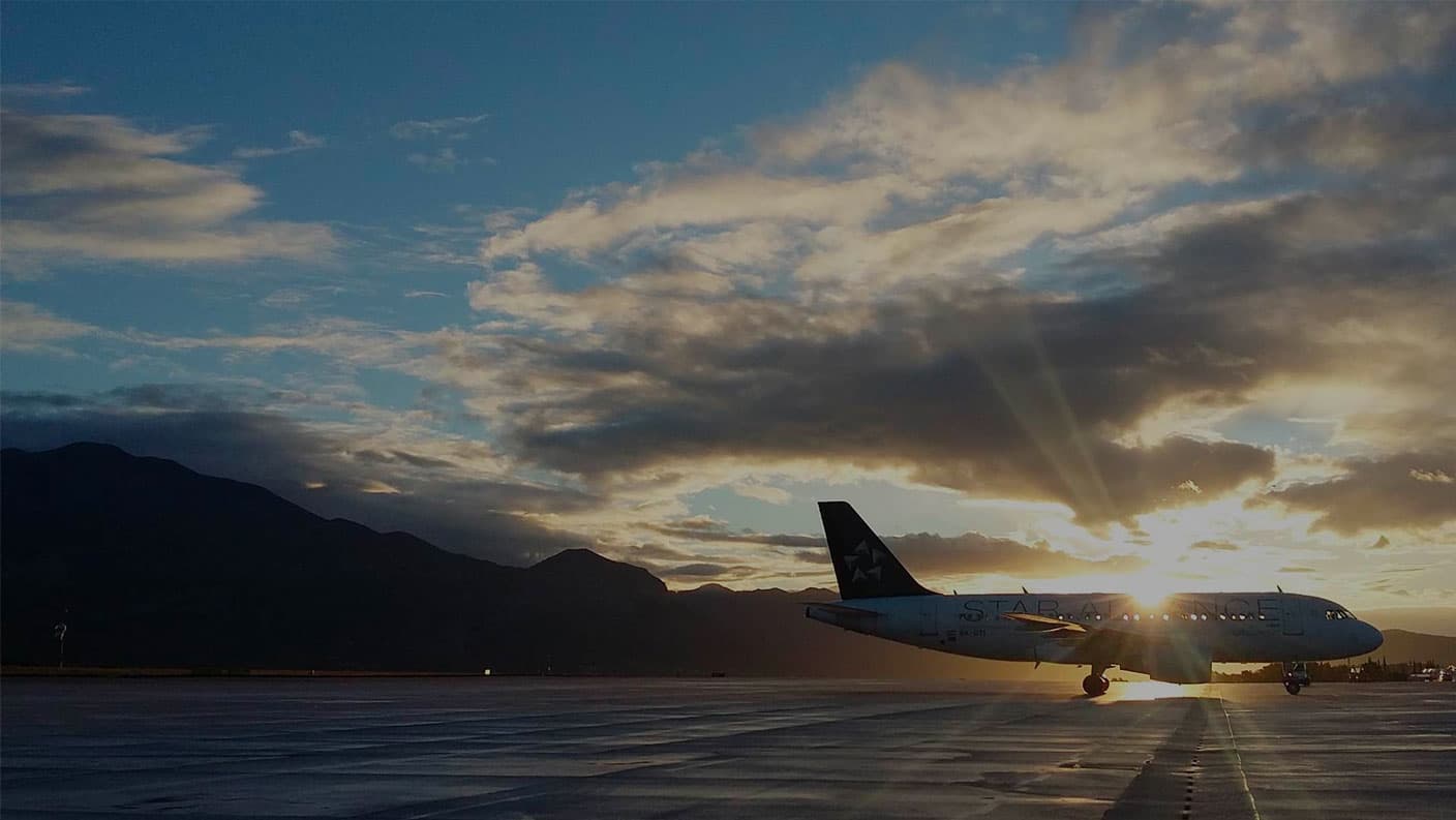 An airplane on the tarmac as the sun breaks through the clouds