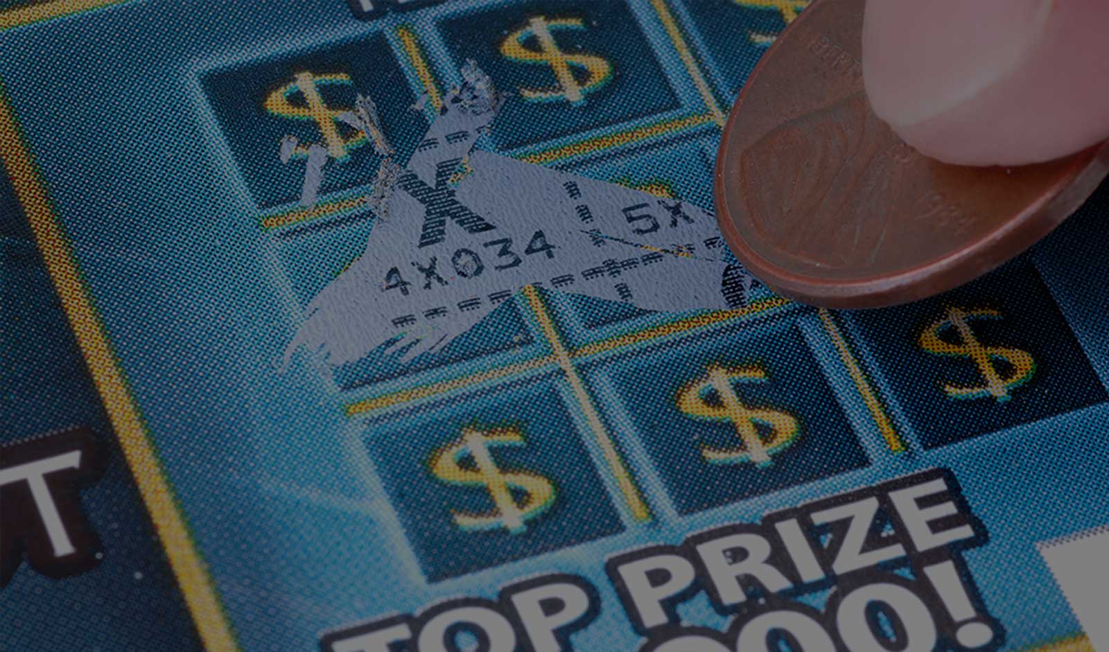 A closeup of a lottery ticket being scratched off with a penny