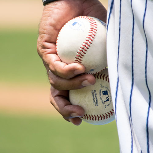 A baseball pitcher holds two baseballs