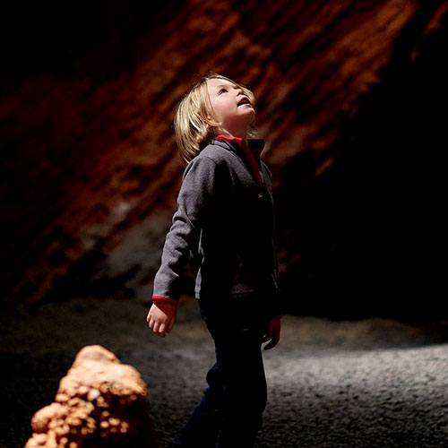 Boy looks in wonder at cave