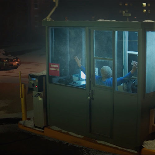 Parking lot booth worker watching screen on a lonely dark winter night