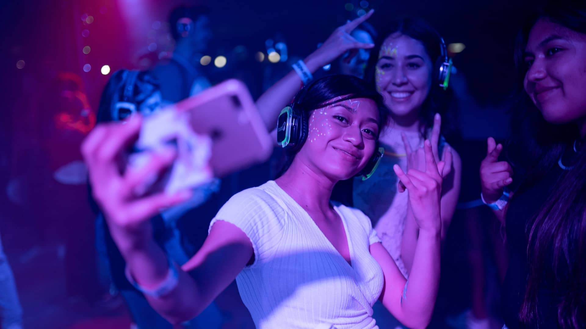 A young woman dances at a concert with her phone